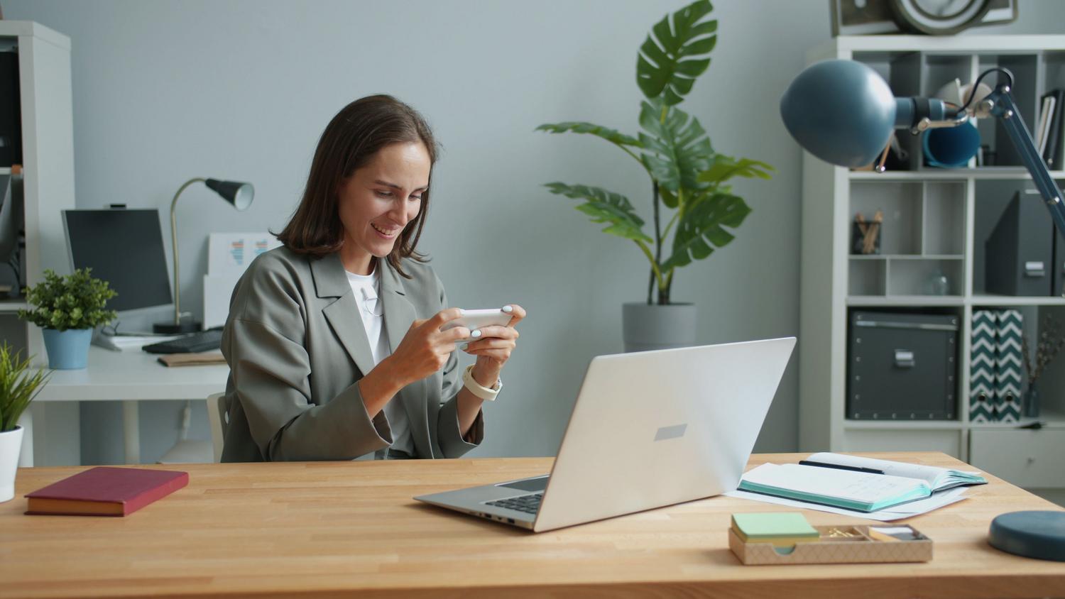 Profesional trabajando desde casa con portátil y smartphone, destacando la flexibilidad de las herramientas en la nube.