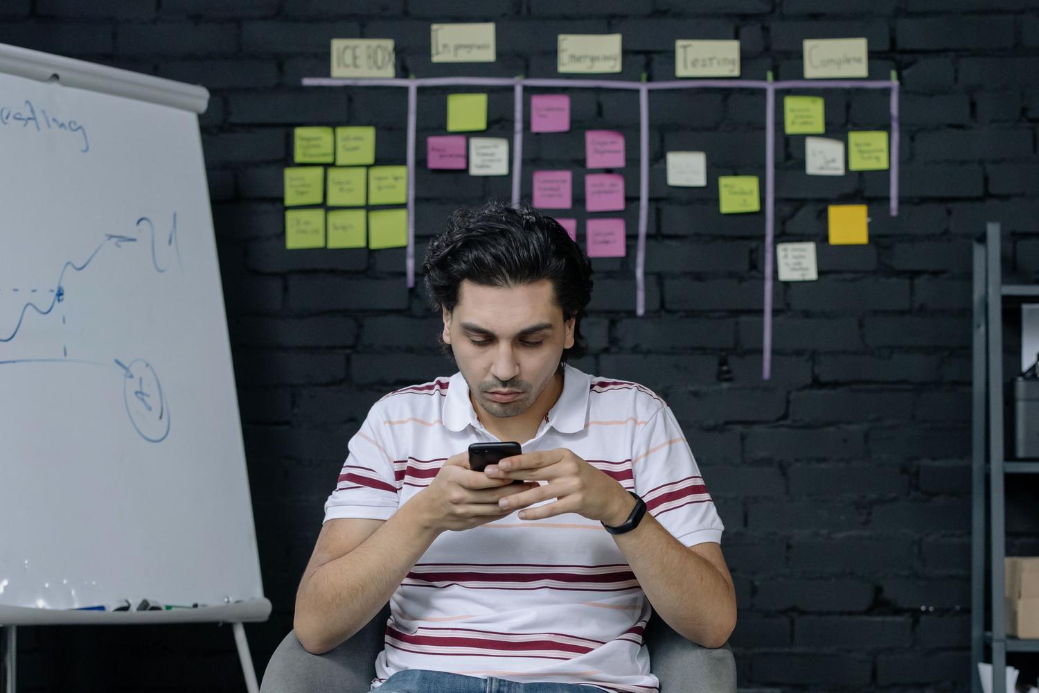 Agente de ventas organizando el flujo de trabajo con notas adhesivas y smartphone, simbolizando el control operativo en WhatsApp.