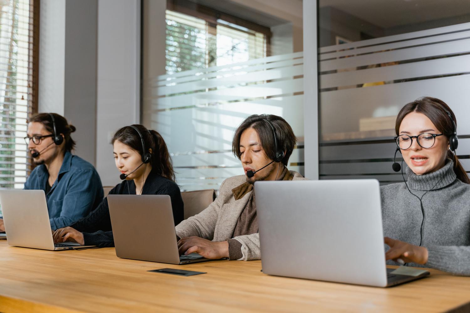 Equipo de agentes de soporte trabajando con ordenadores en una oficina moderna, ilustrando la gestión profesional con la API de WhatsApp Business.