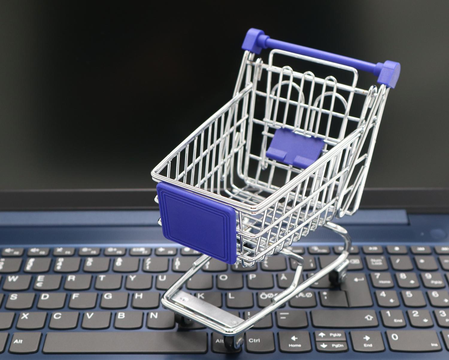 Concepto de tienda online con un carrito de compras sobre el teclado de una laptop, simbolizando el e-commerce de productos digitales.