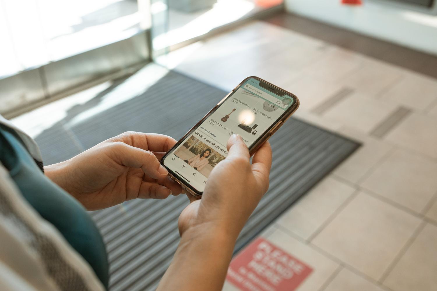 Primer plano de unas manos sosteniendo un smartphone con una aplicación de compras online, representando la facilidad de compra inmediata en TikTok Shop. Primer plano de unas manos sosteniendo un smartphone con una aplicación de compras online, representando la facilidad de compra inmediata en TikTok Shop.