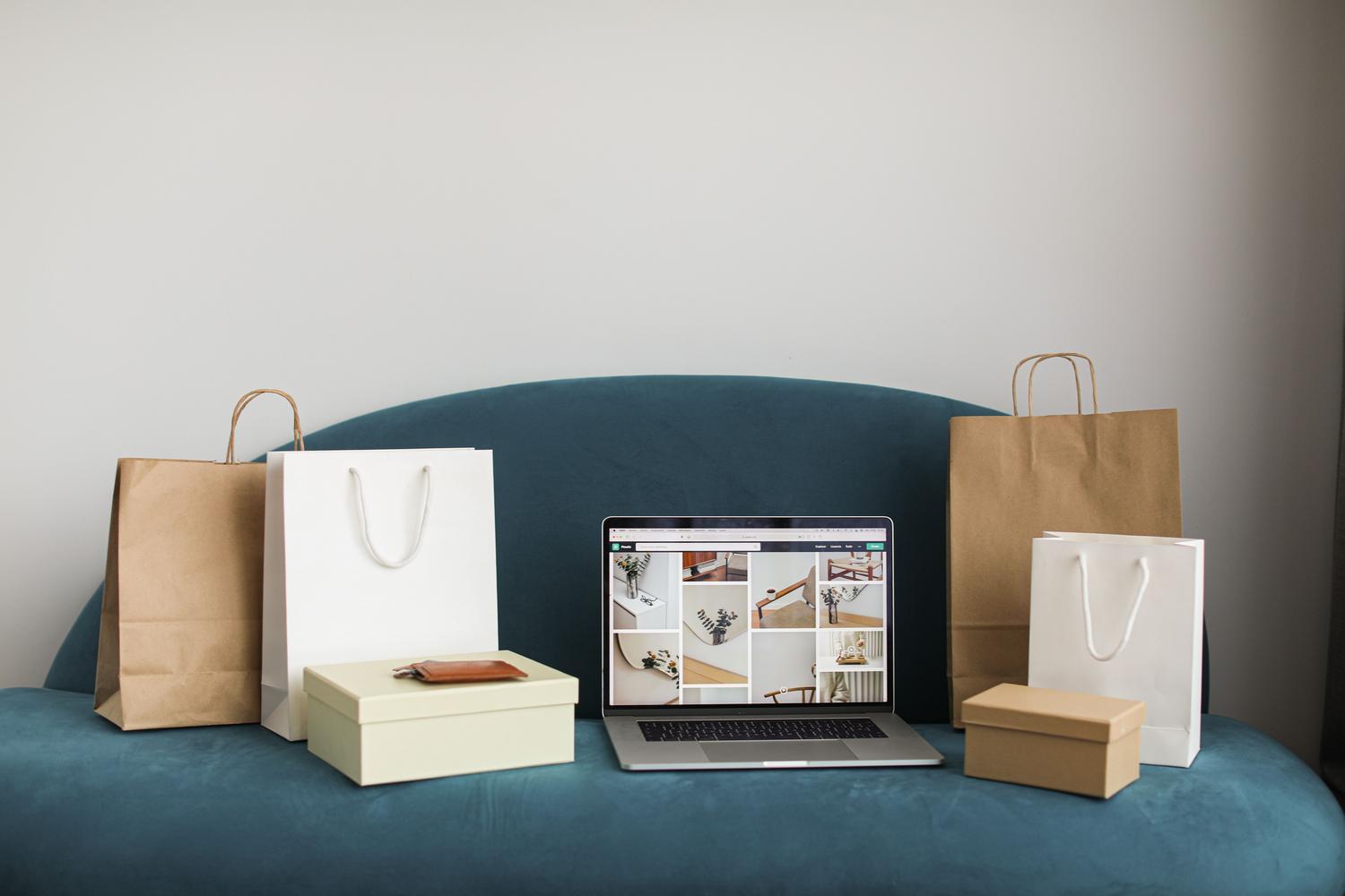 Laptop rodeado de bolsas de compras, simbolizando la conversión de tráfico de Pinterest a ventas en una tienda Shopify.