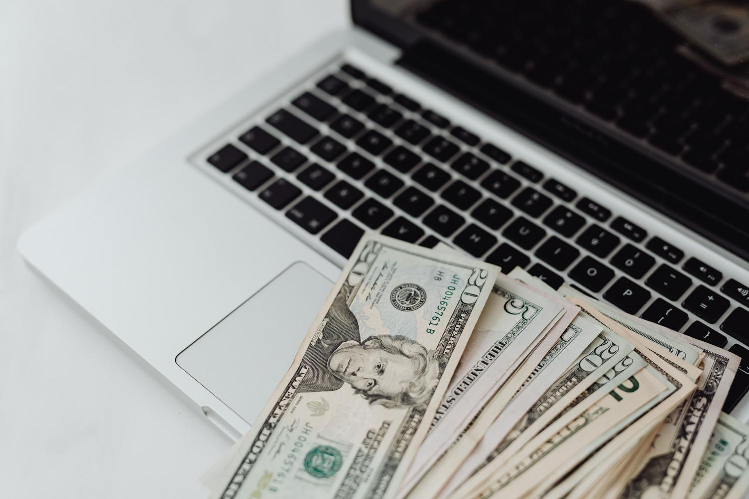 US dollar bills on a laptop keyboard symbolizing digital monetization and online income.