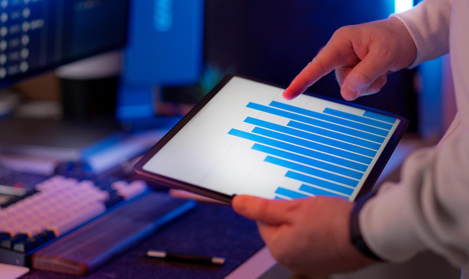 Profesional de marketing analizando gráficos de barras en una tablet para realizar una segmentación inteligente de audiencias.