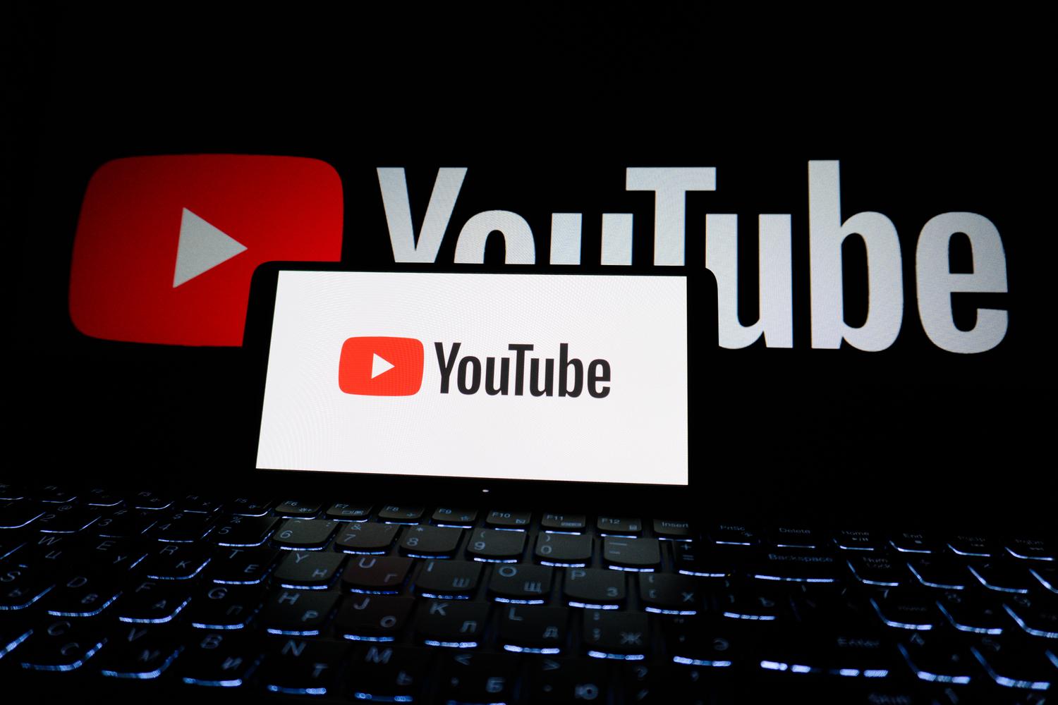 Primer plano del logotipo de YouTube en la pantalla de un ordenador portátil en un ambiente oscuro, centrando la atención en la plataforma.