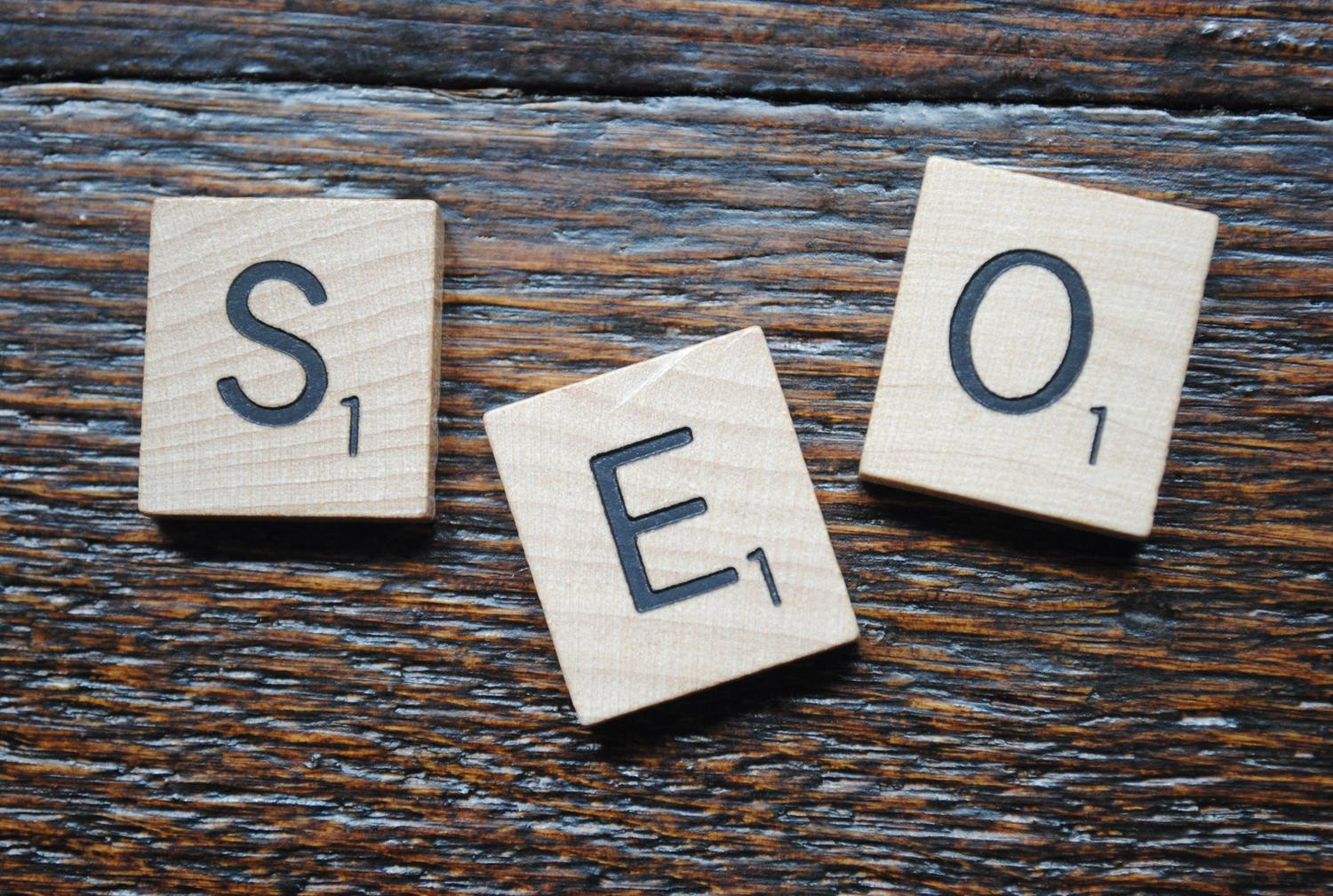 Fichas de Scrabble formando la palabra SEO sobre una mesa de madera, ilustrando la optimización para motores de búsqueda.