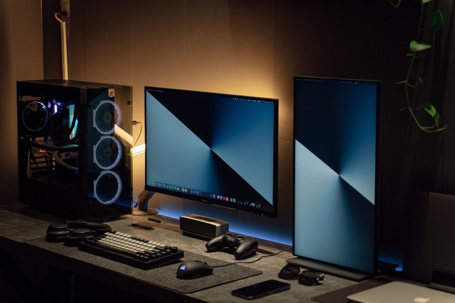 Setup de gaming completo con PC, monitores y mando, contextualizando el entorno de actualización de firmware.