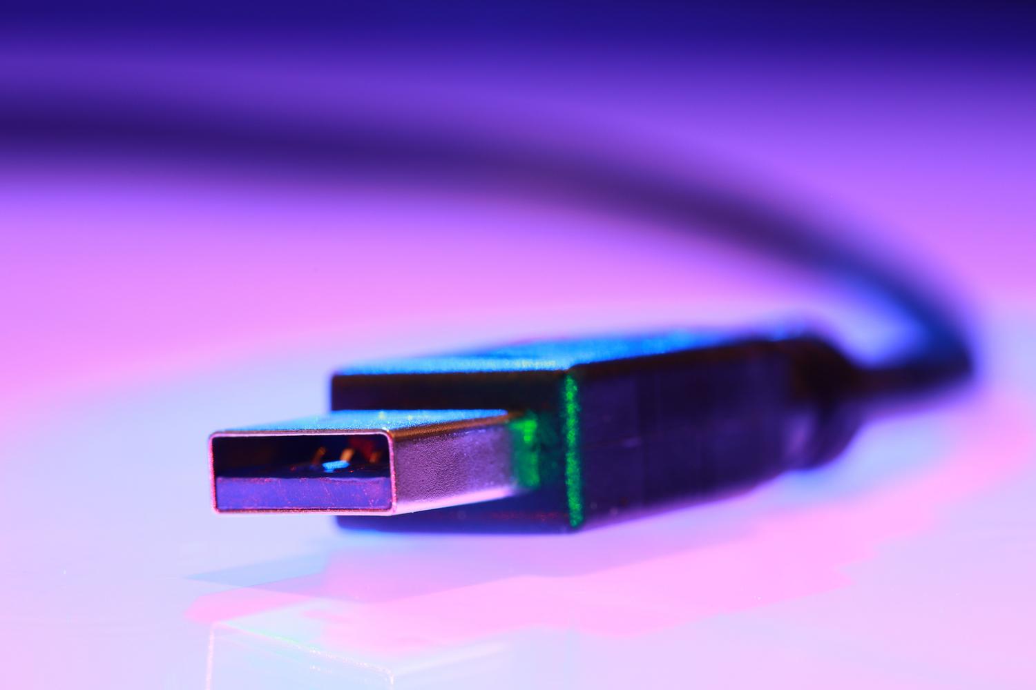 Primer plano macro de un conector USB Tipo-A con iluminación neón, enfatizando la necesidad de conexión por cable.