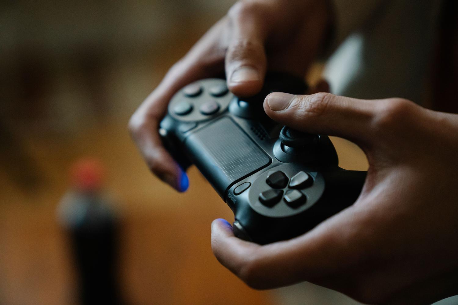 Persona sosteniendo un mando de videojuegos en un entorno doméstico relajado.