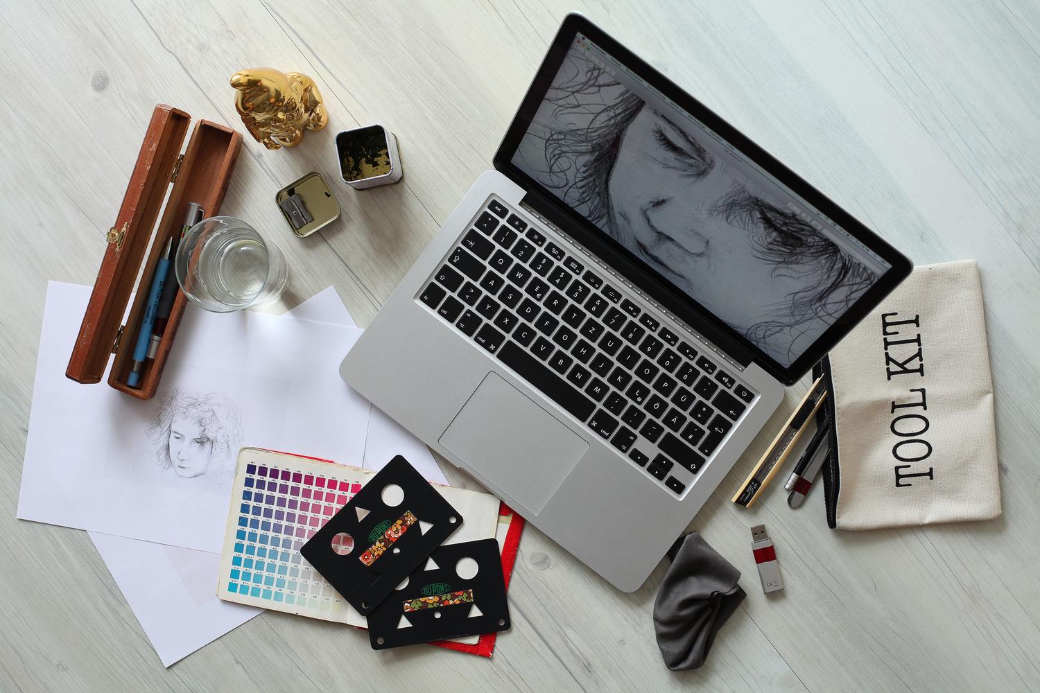 Espacio de trabajo creativo con portátil y una paleta de colores física, ideal para ilustrar el flujo de trabajo de un diseñador.