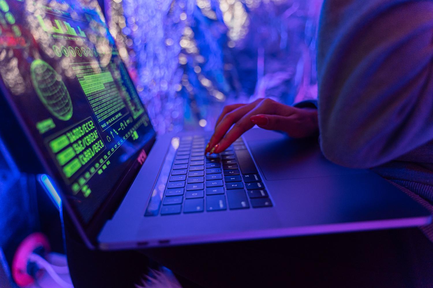 Person using a laptop with cybersecurity graphics, illustrating ransomware threats and digital attacks.