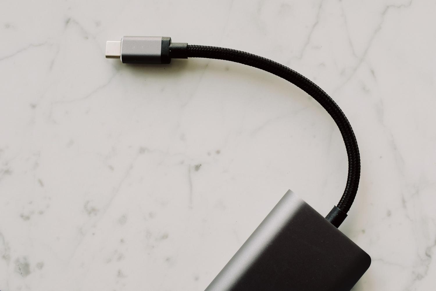 Primer plano de un cable USB-C sobre una superficie blanca, destacando el conector físico.