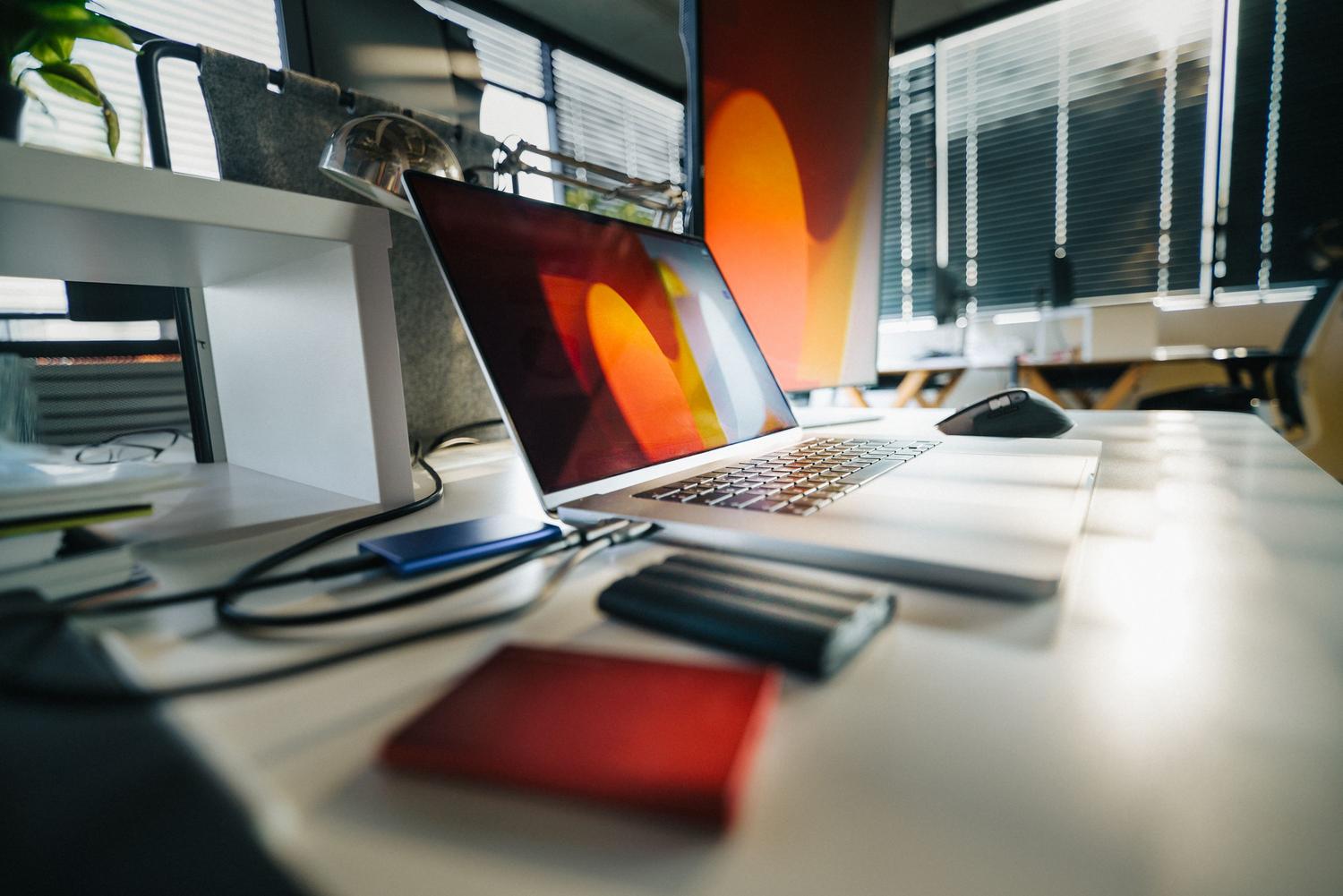 Espacio de trabajo profesional moderno con un portátil y varias unidades de almacenamiento externas, simbolizando la estrategia de almacenamiento híbrido.