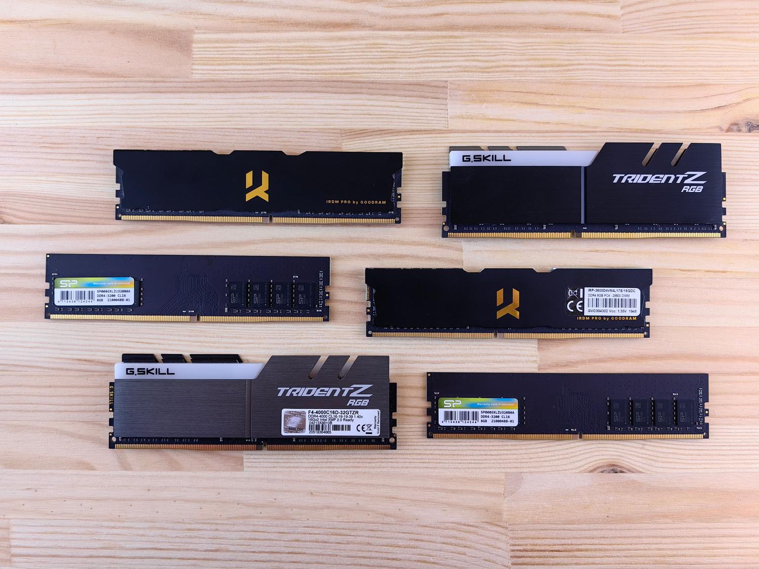 Varios módulos de memoria RAM de diferentes marcas y tipos sobre una superficie de madera, ilustrando la variedad de opciones disponibles.