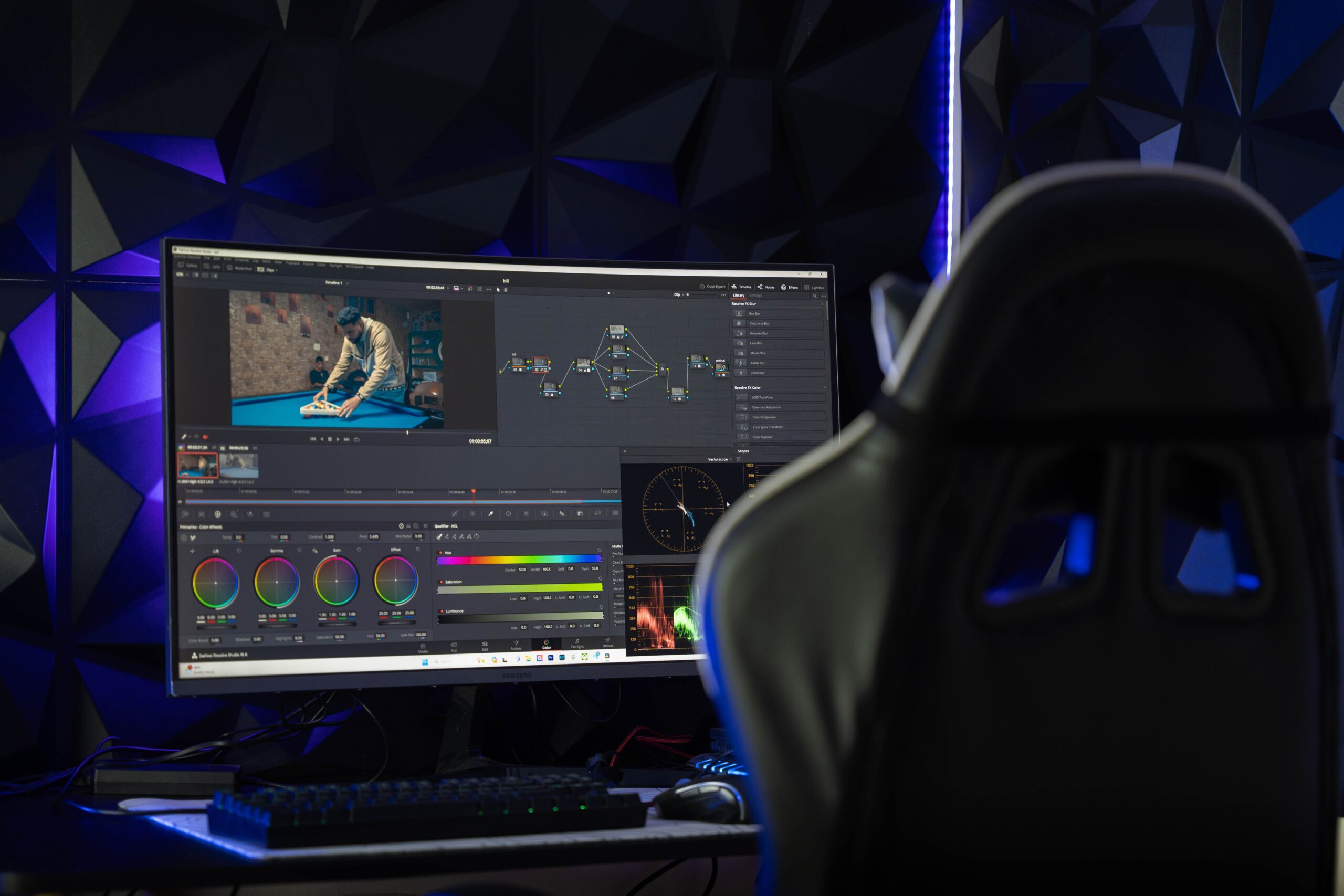 Monitor curvo ultrapanorámico mostrando software de edición de vídeo en un espacio de trabajo tecnológico con iluminación ambiental.