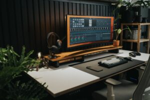 Espacio de trabajo moderno y minimalista con un monitor ultrapanorámico, teclado y plantas, ideal para creadores de contenido.