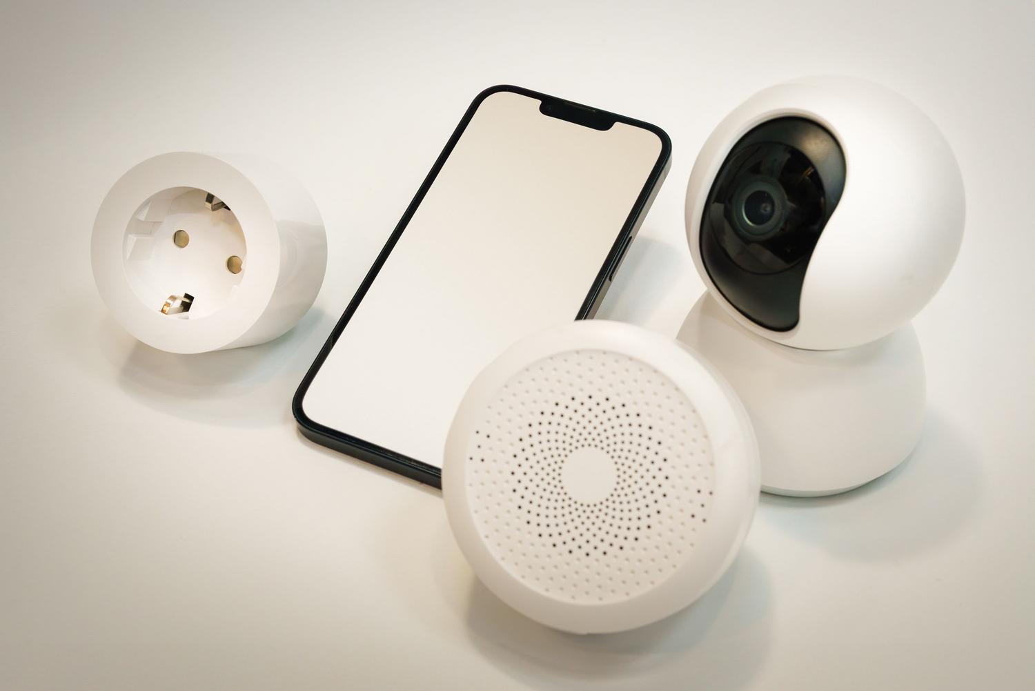 Conjunto de dispositivos de hogar inteligente como cámaras y altavoces sobre un fondo blanco.