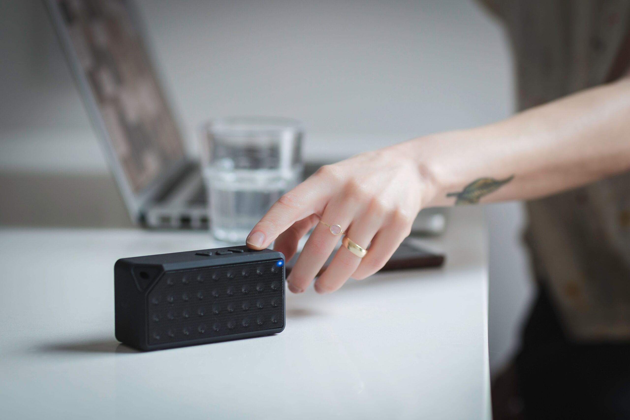 Persona configurando un altavoz Bluetooth portátil junto a una laptop