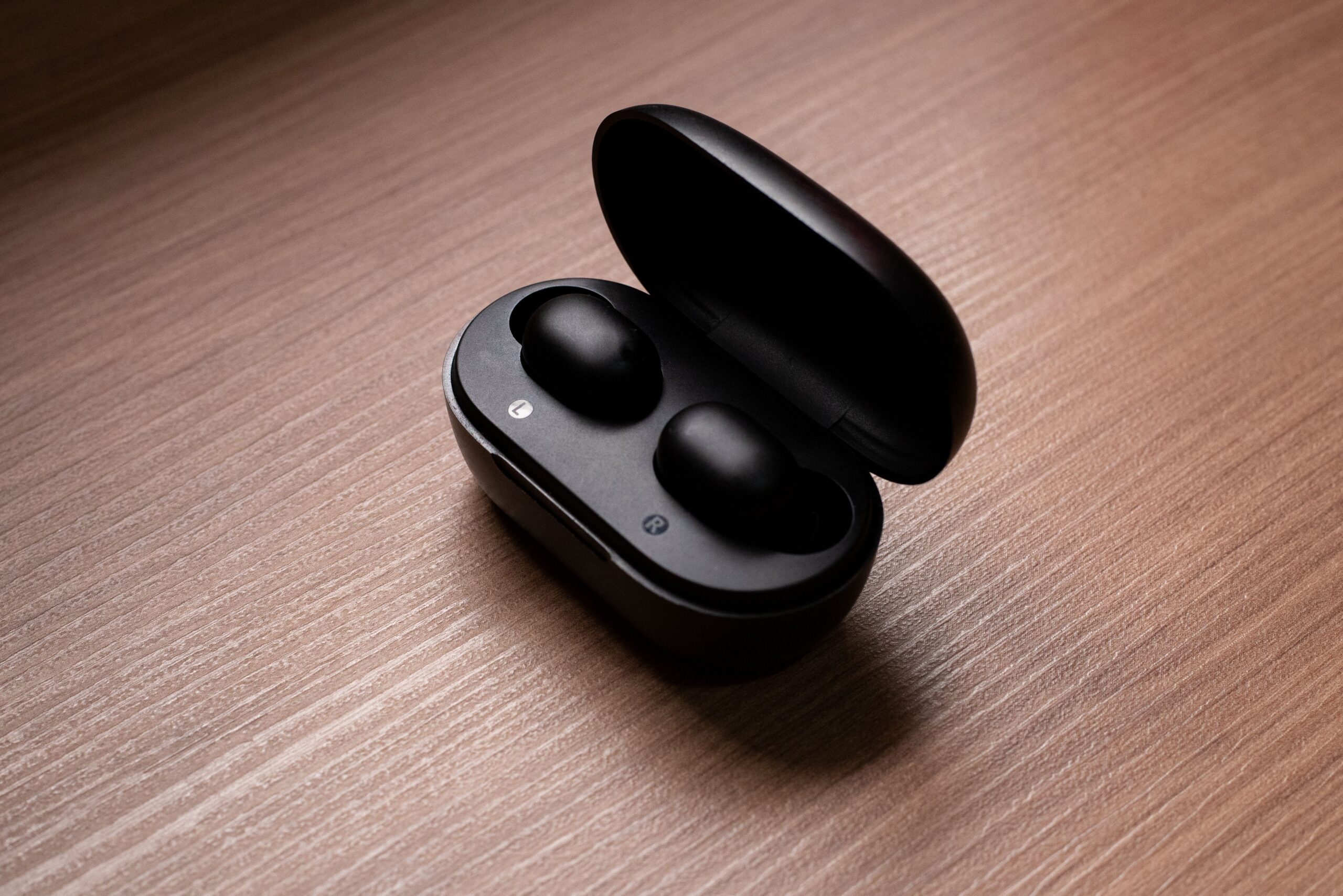 Auriculares inalámbricos en su estuche de carga sobre una mesa de madera