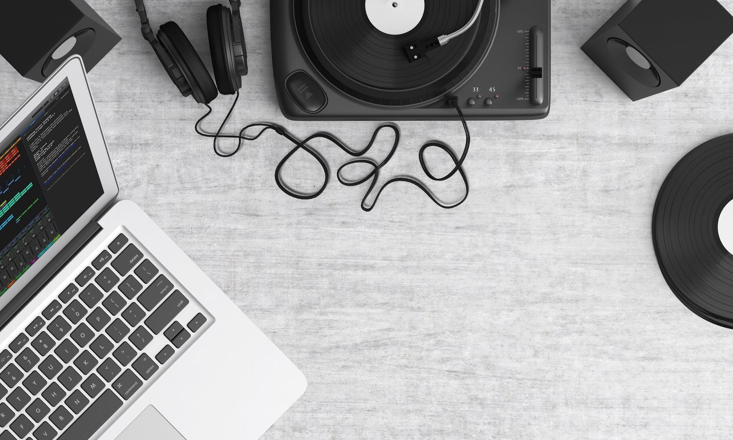 Vista cenital de un espacio de trabajo musical con laptop y auriculares, ilustrando las herramientas esenciales del productor.