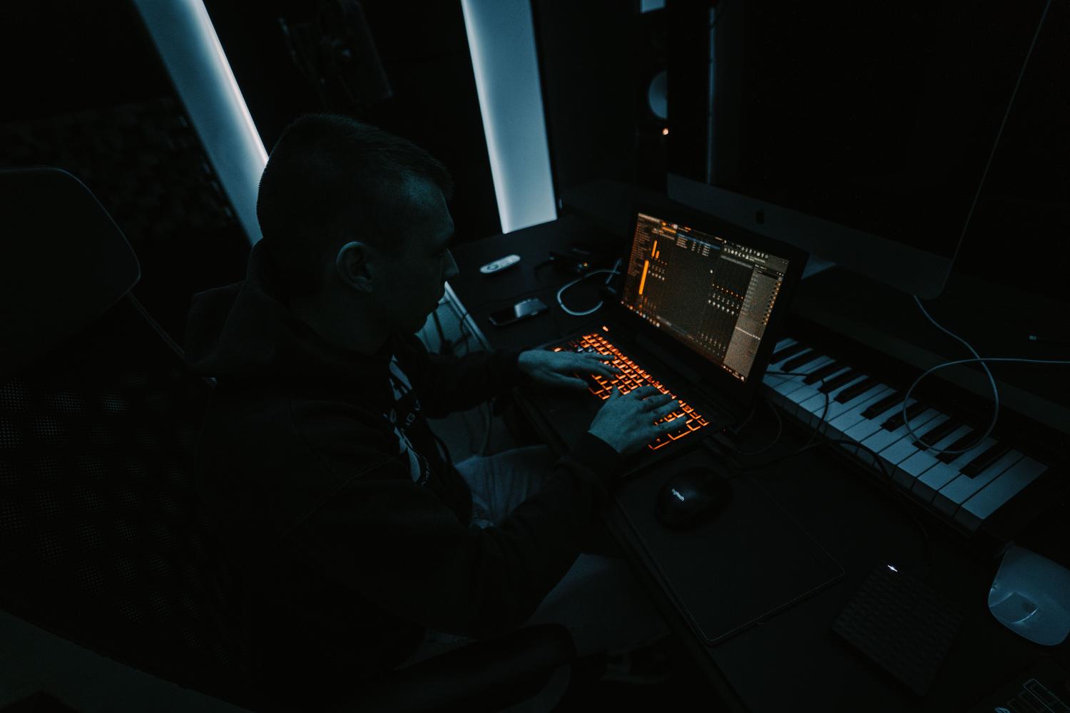 Productor musical trabajando en un estudio casero con un DAW en la pantalla, ilustrando el entorno donde la latencia de audio es un problema común.