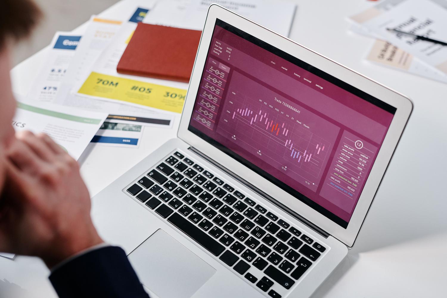 Analista experto evaluando gráficas de datos complejos en un ordenador portátil para la toma de decisiones
