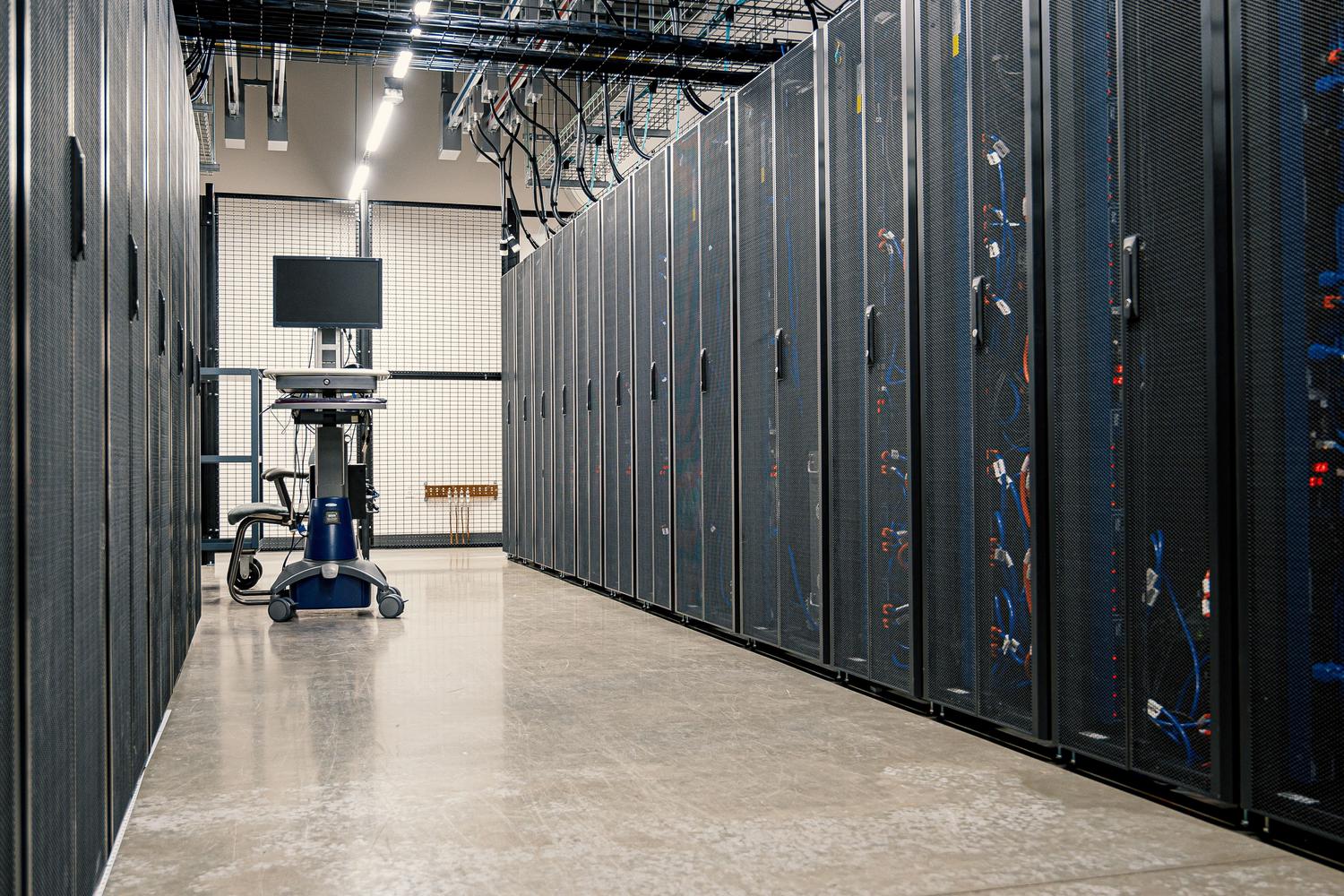 Vista general de un centro de datos empresarial con racks de servidores y equipo de gestión móvil.