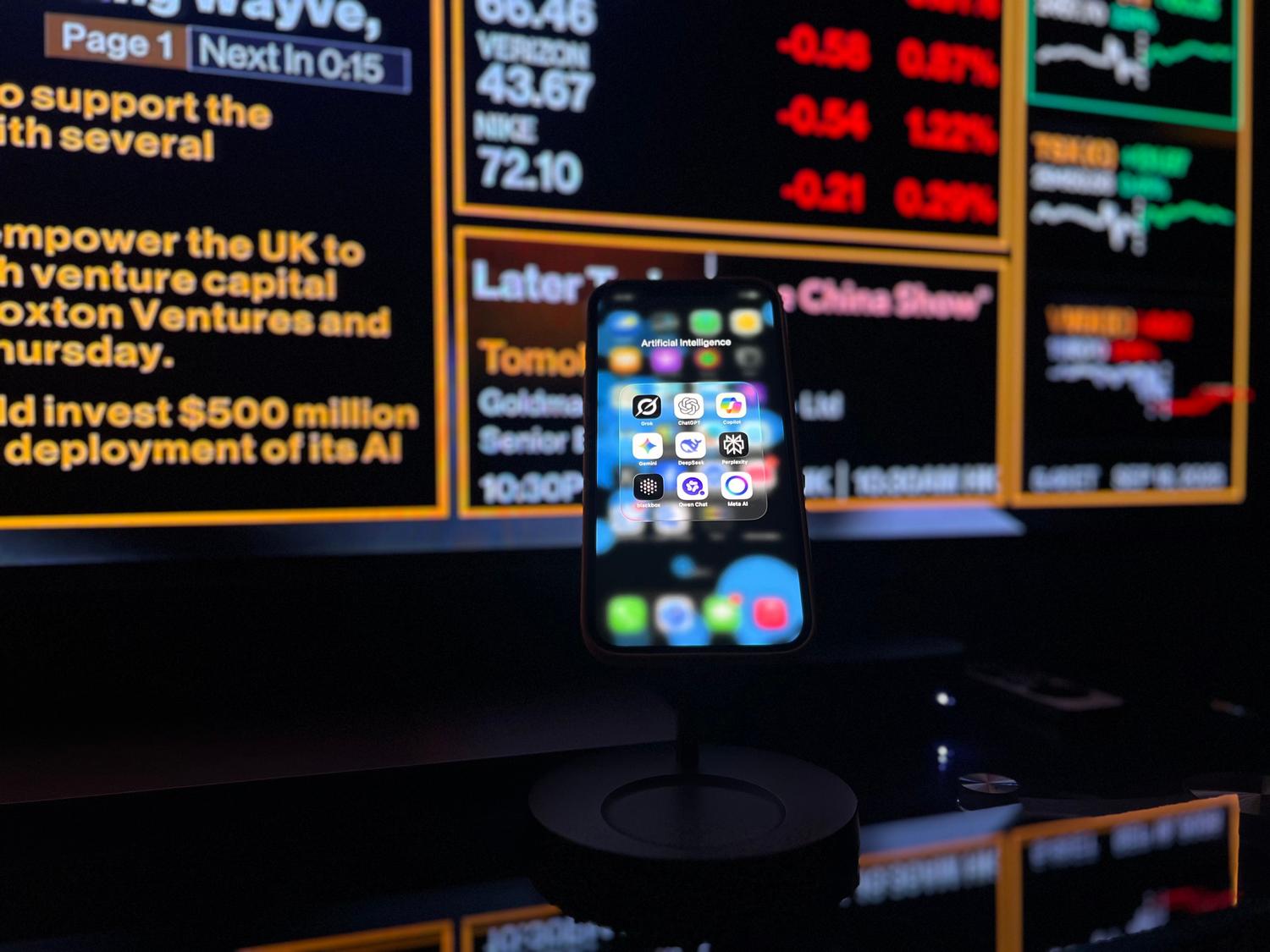 Smartphone mostrando aplicaciones de inteligencia artificial frente a un panel de control de datos financieros.