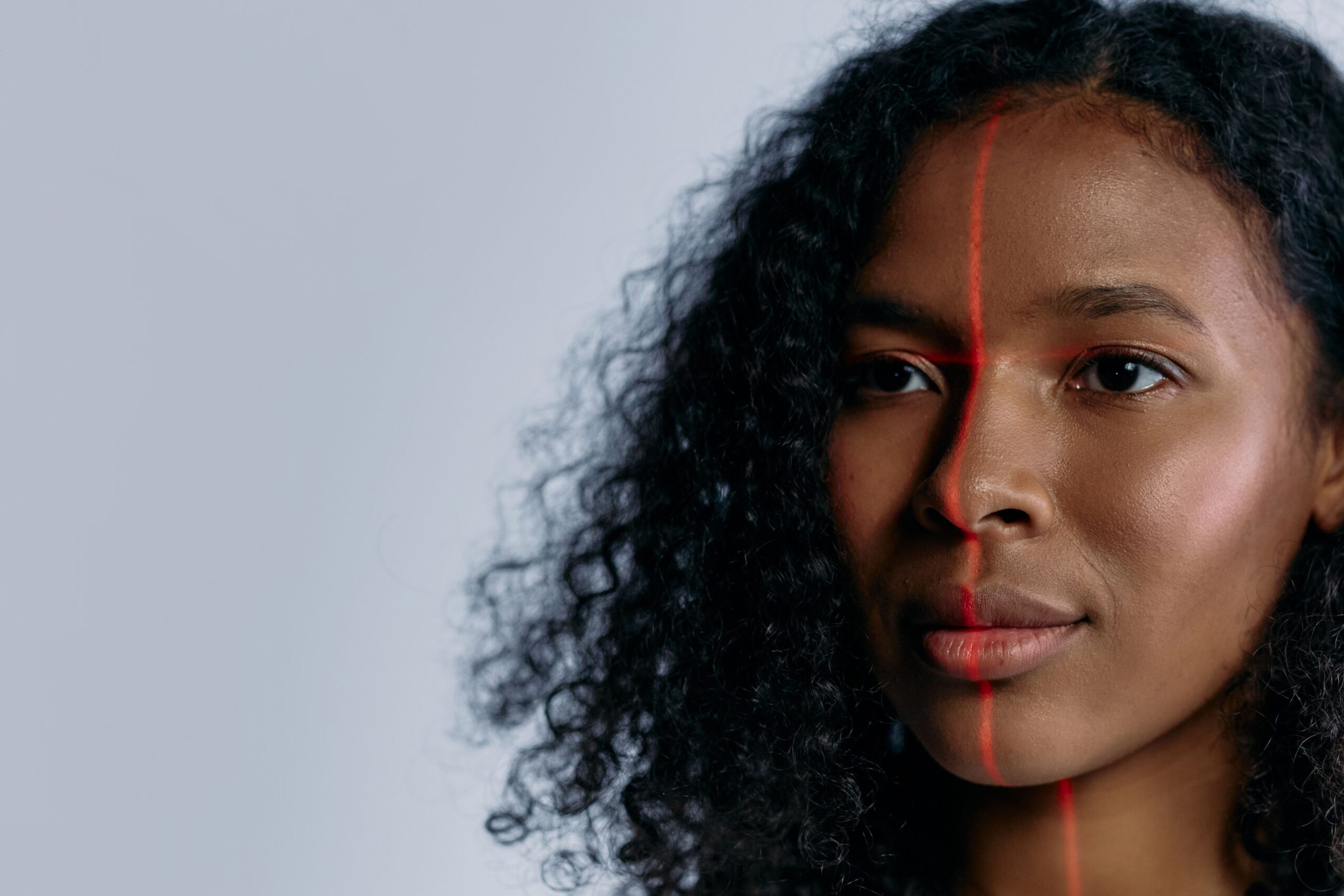 Primer plano de una mujer siendo escaneada con un láser para el reconocimiento facial, ilustrando la biometría avanzada.
