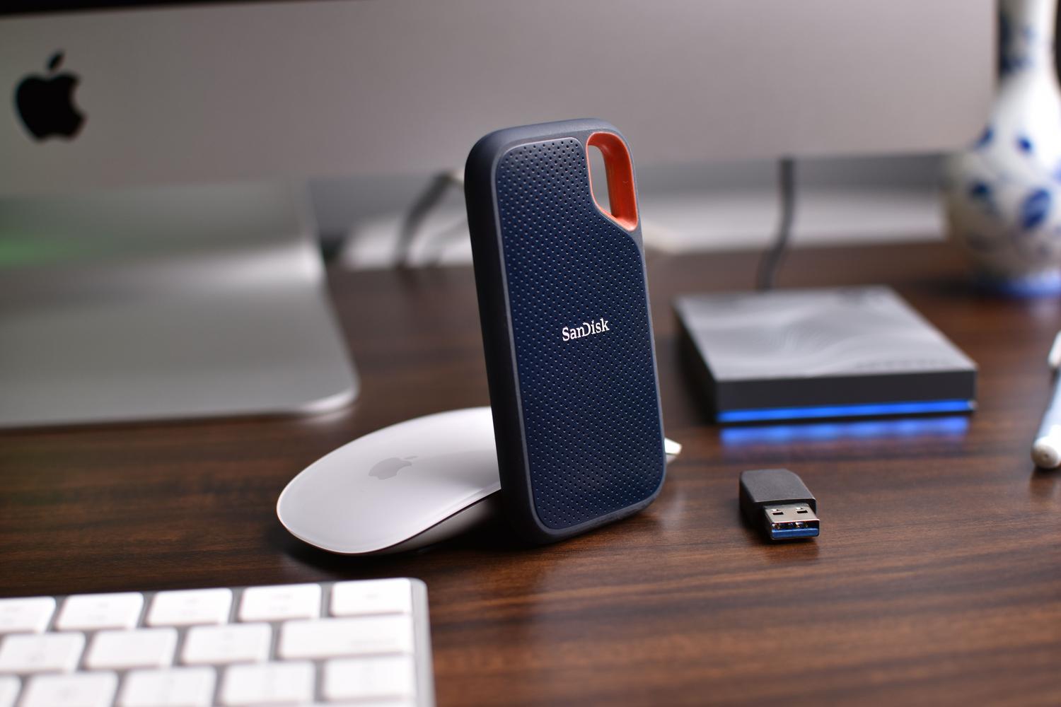 Accesorios electrónicos en un escritorio, incluyendo discos duros externos y memorias USB.