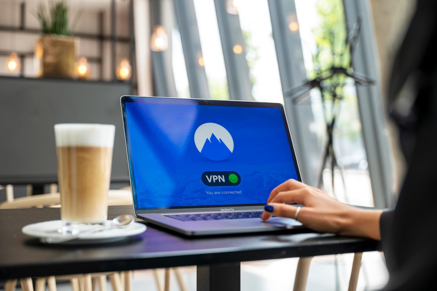 Persona utilizando un portátil en una cafetería, ilustrando el acceso remoto a archivos desde fuera de casa.