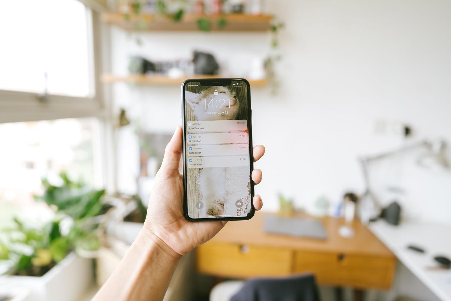 Primer plano de una mano sosteniendo un smartphone con notificaciones, representando las alertas instantáneas en el móvil.
