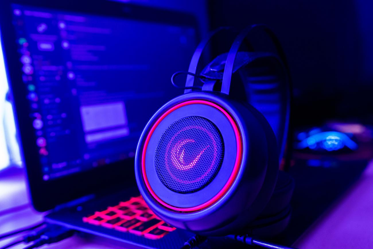 Auriculares gaming con iluminación neón junto a un portátil, cubriendo el contexto de fallos de audio en videojuegos tras actualizar el sistema.