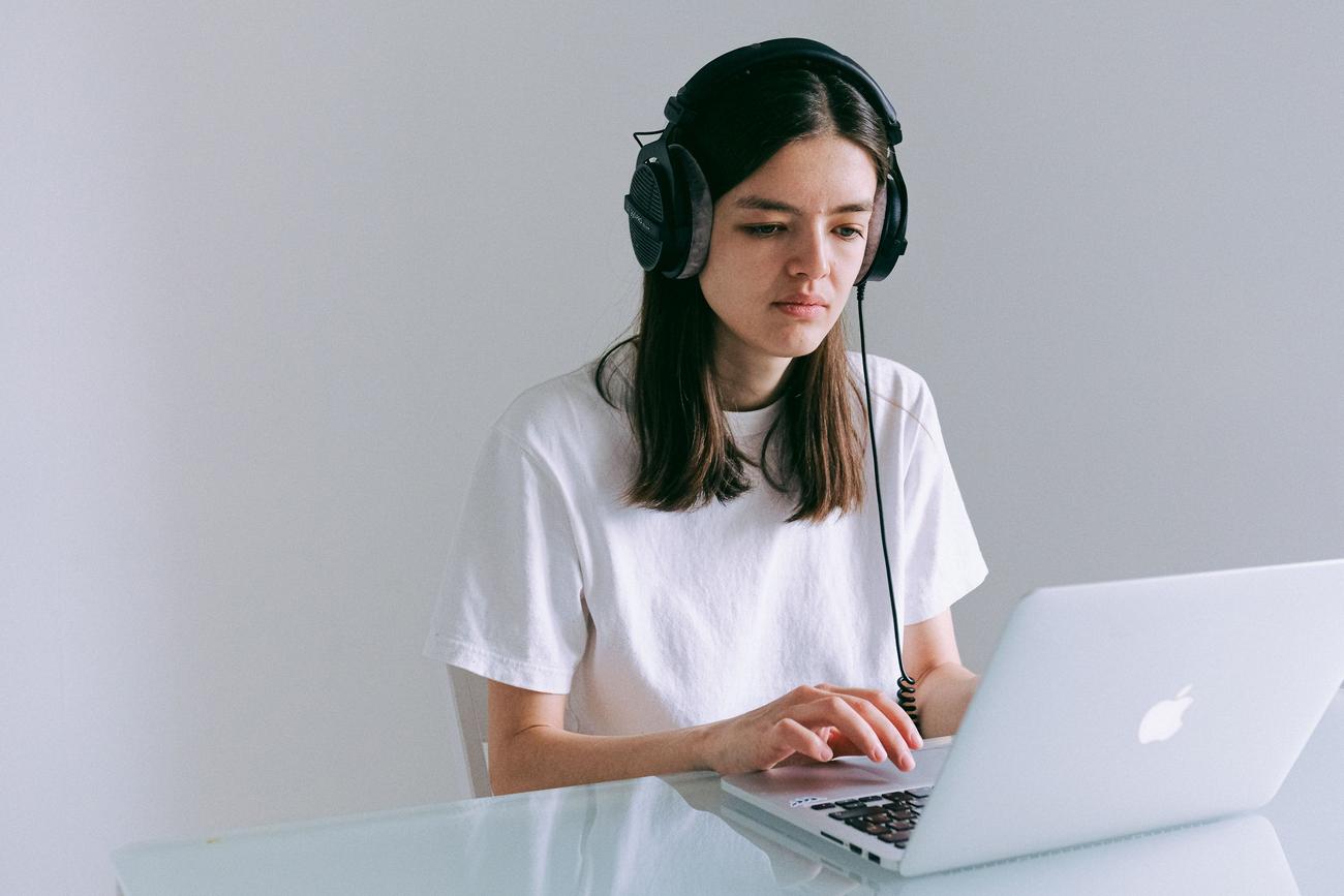 Mujer trabajando en su oficina en casa con auriculares y portátil, ilustrando el uso cotidiano del audio en videollamadas y trabajo remoto.