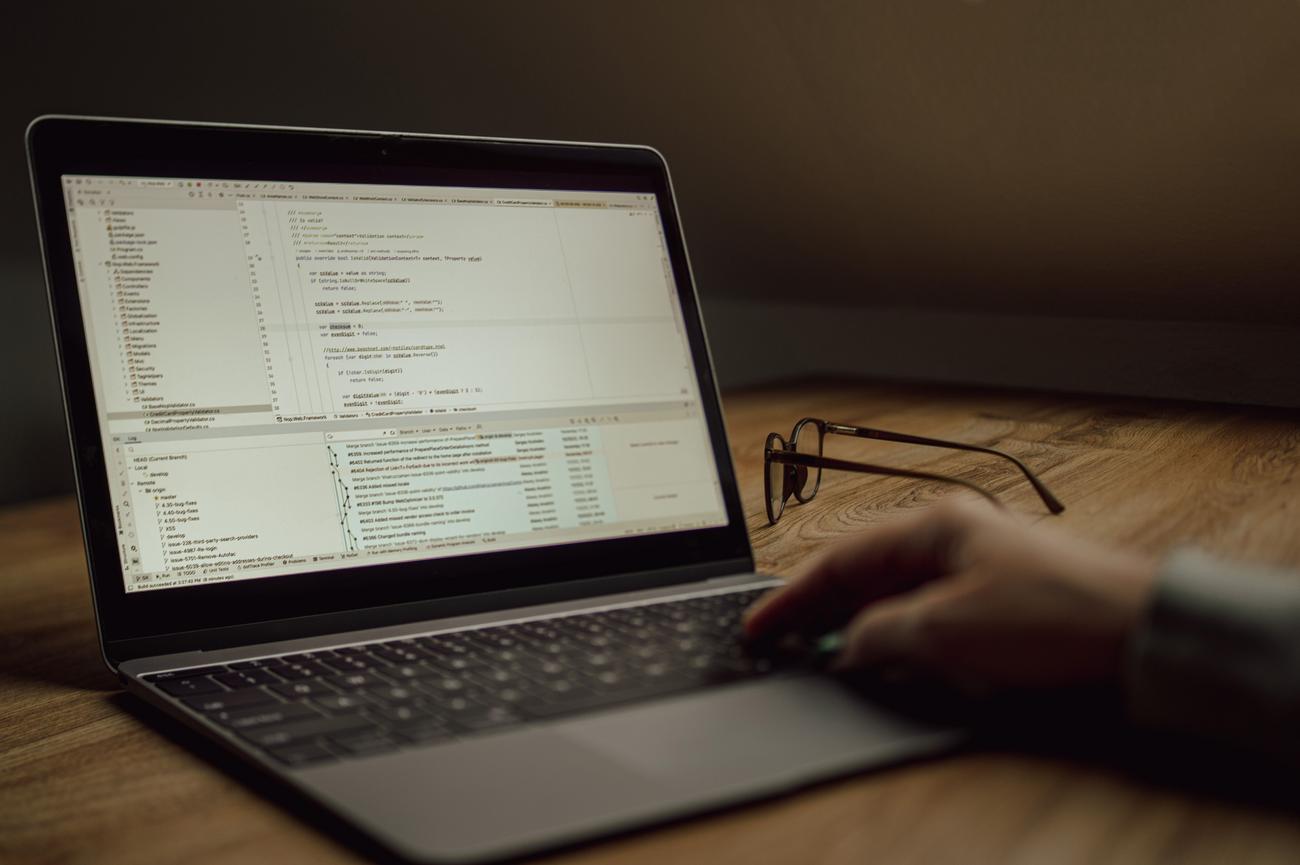 Programador trabajando en el código de una aplicación en un portátil en un entorno de oficina moderno.