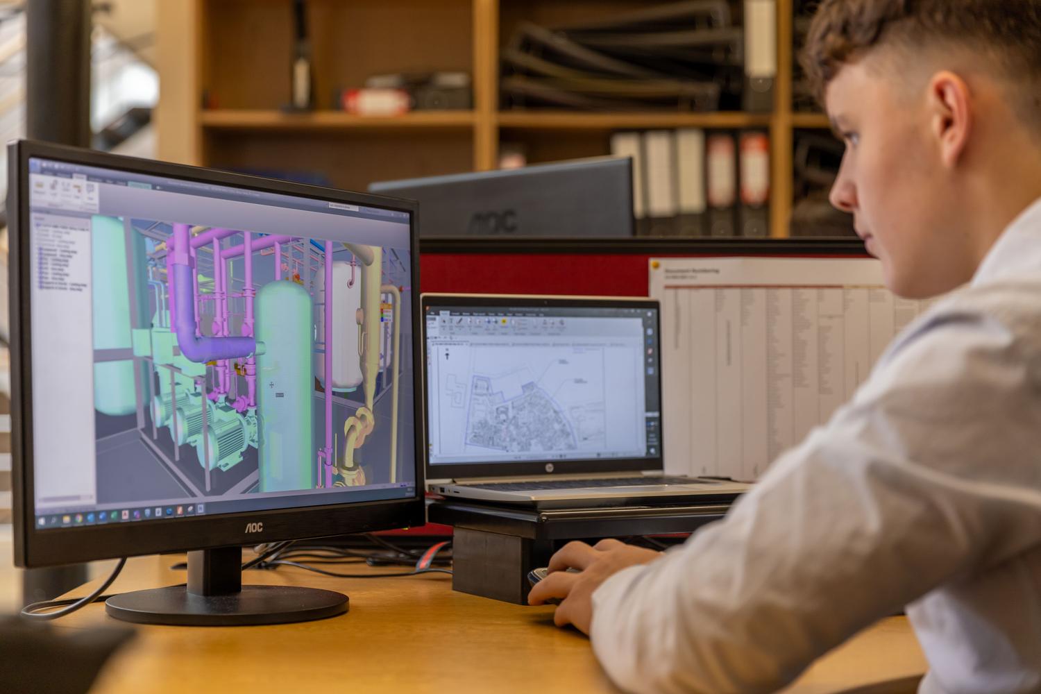 Ingeniero trabajando con software CAD en un entorno de oficina profesional con monitores duales