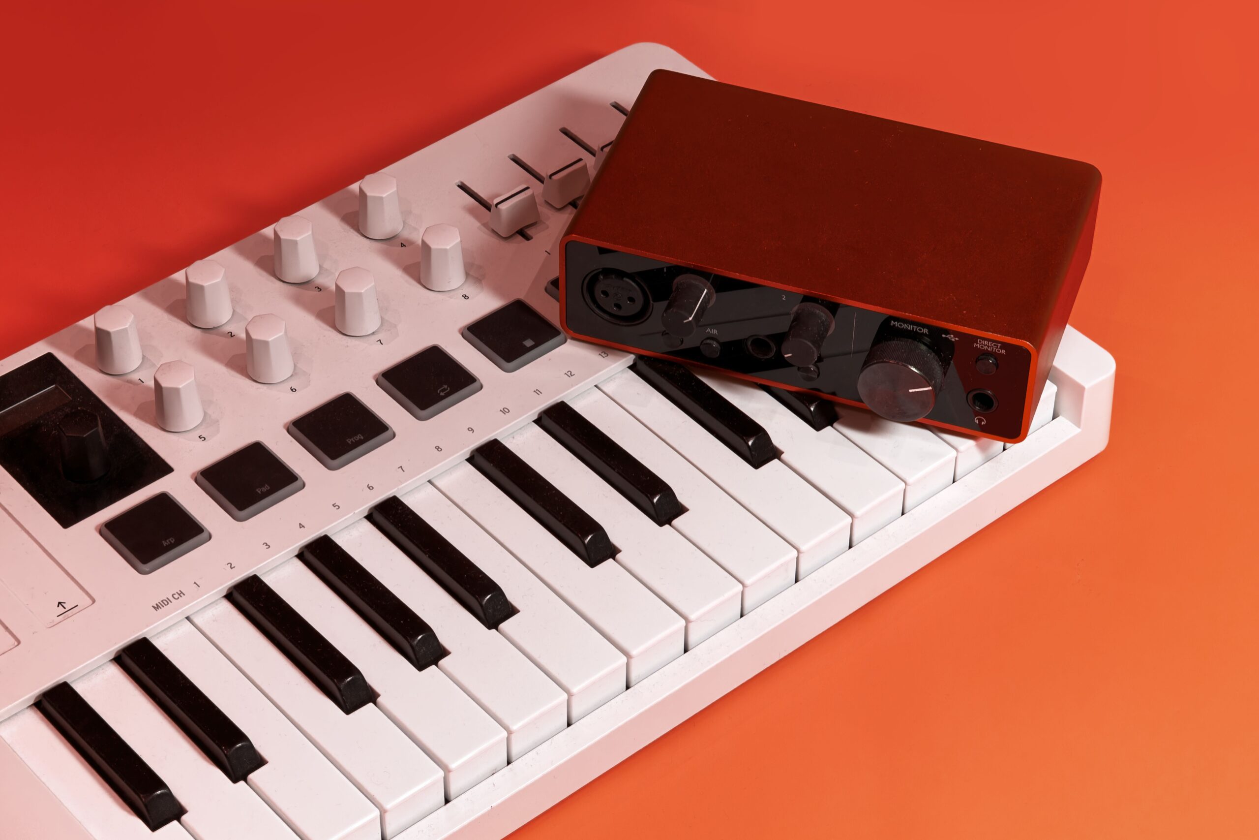 Teclado MIDI blanco junto a una interfaz de audio profesional