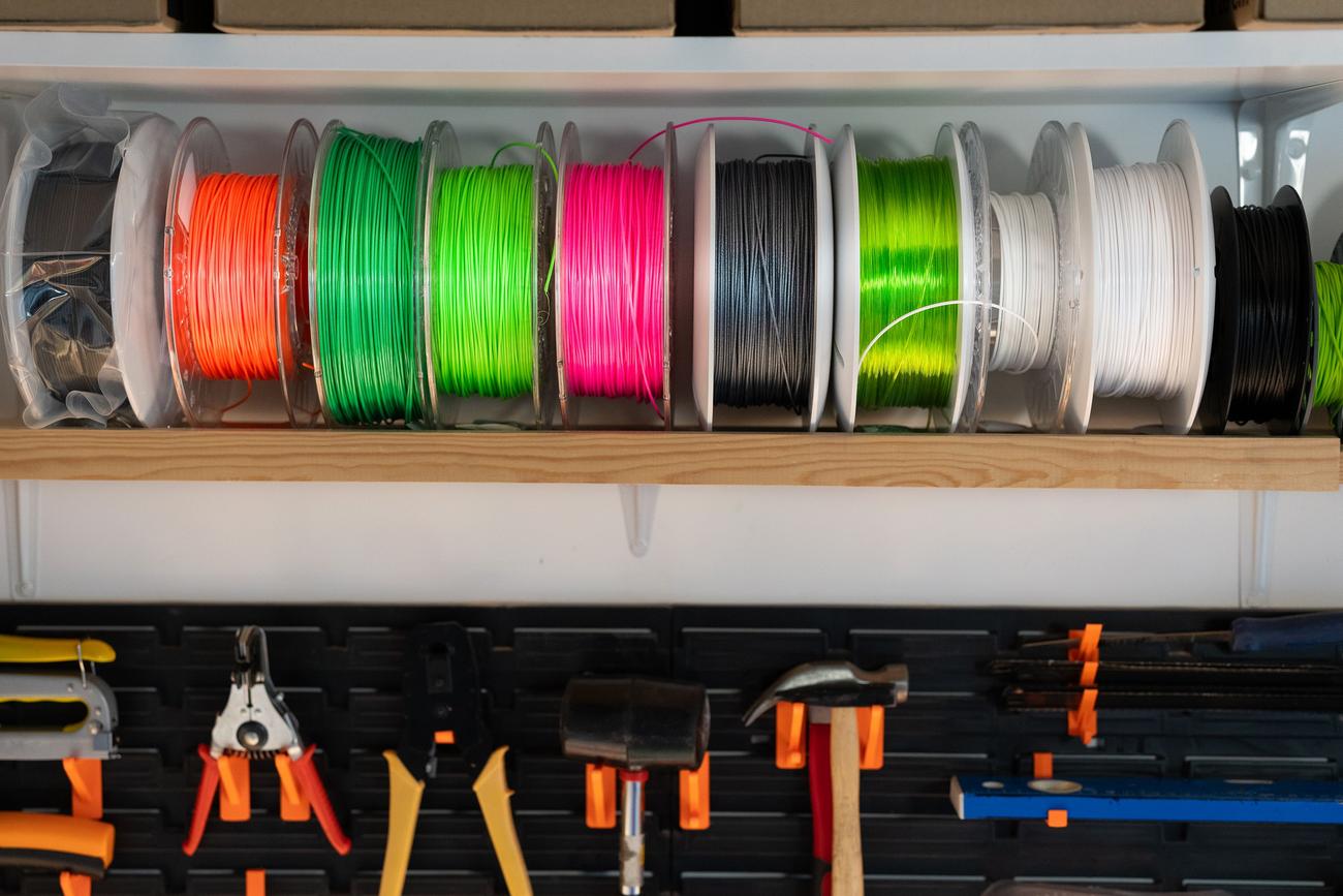 Bobinas de filamento de colores organizadas en un taller, representando la importancia de la calidad del material en la impresión 3D.