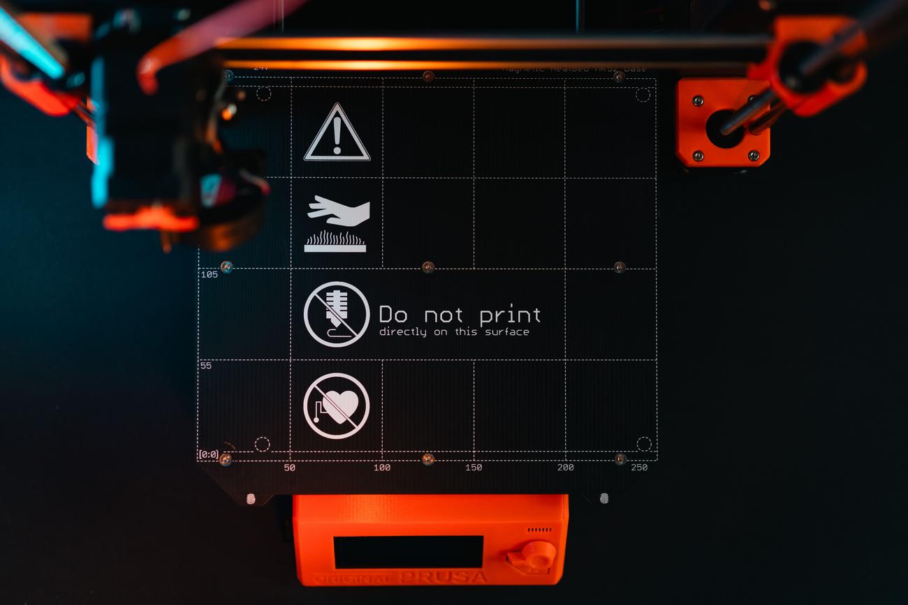 Plataforma de impresión 3D con símbolos de advertencia, ilustrando la zona de calibración y nivelado de la cama.