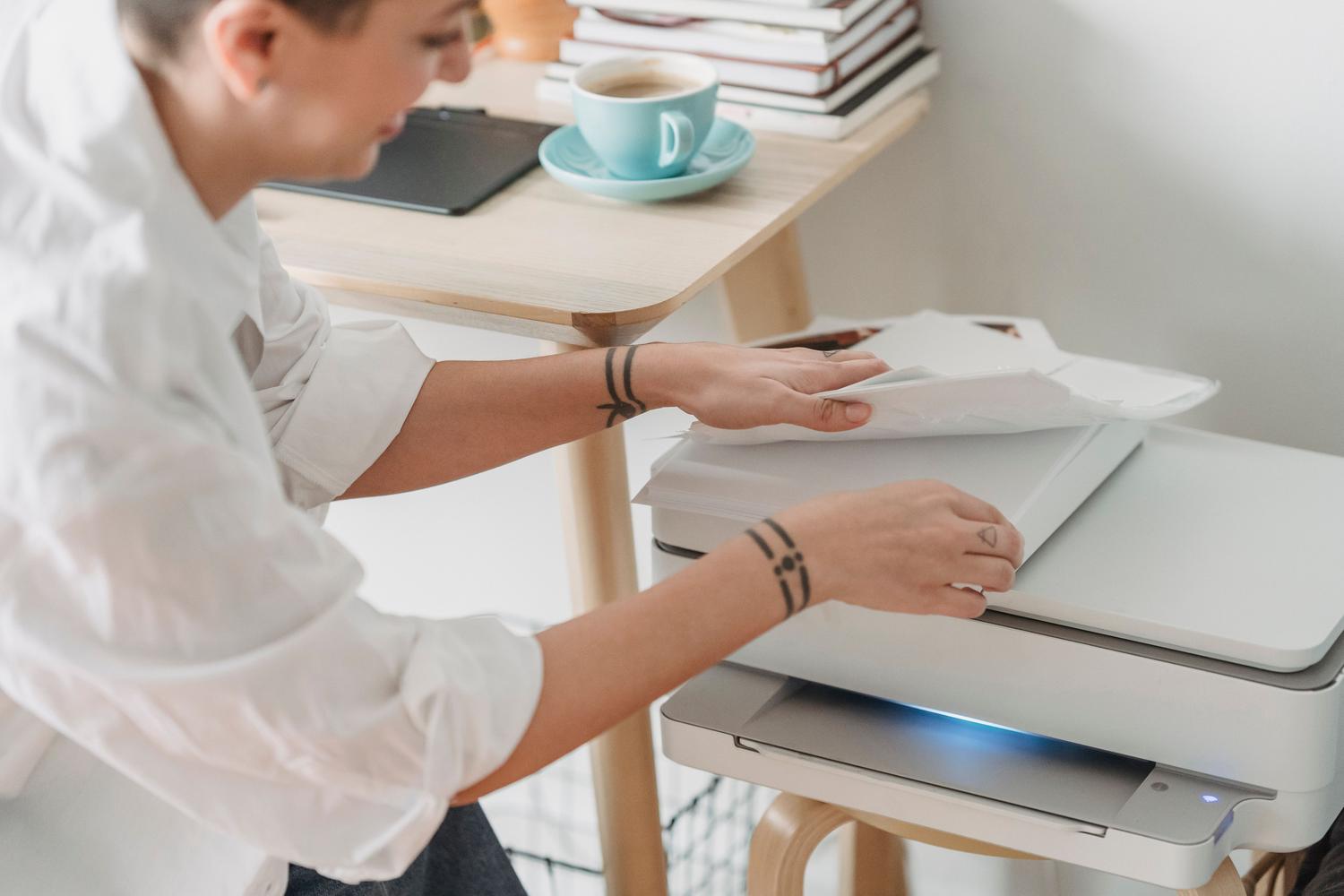 Persona cargando papel en una impresora, representando la optimización del soporte y el ahorro de papel mediante la impresión a doble cara.