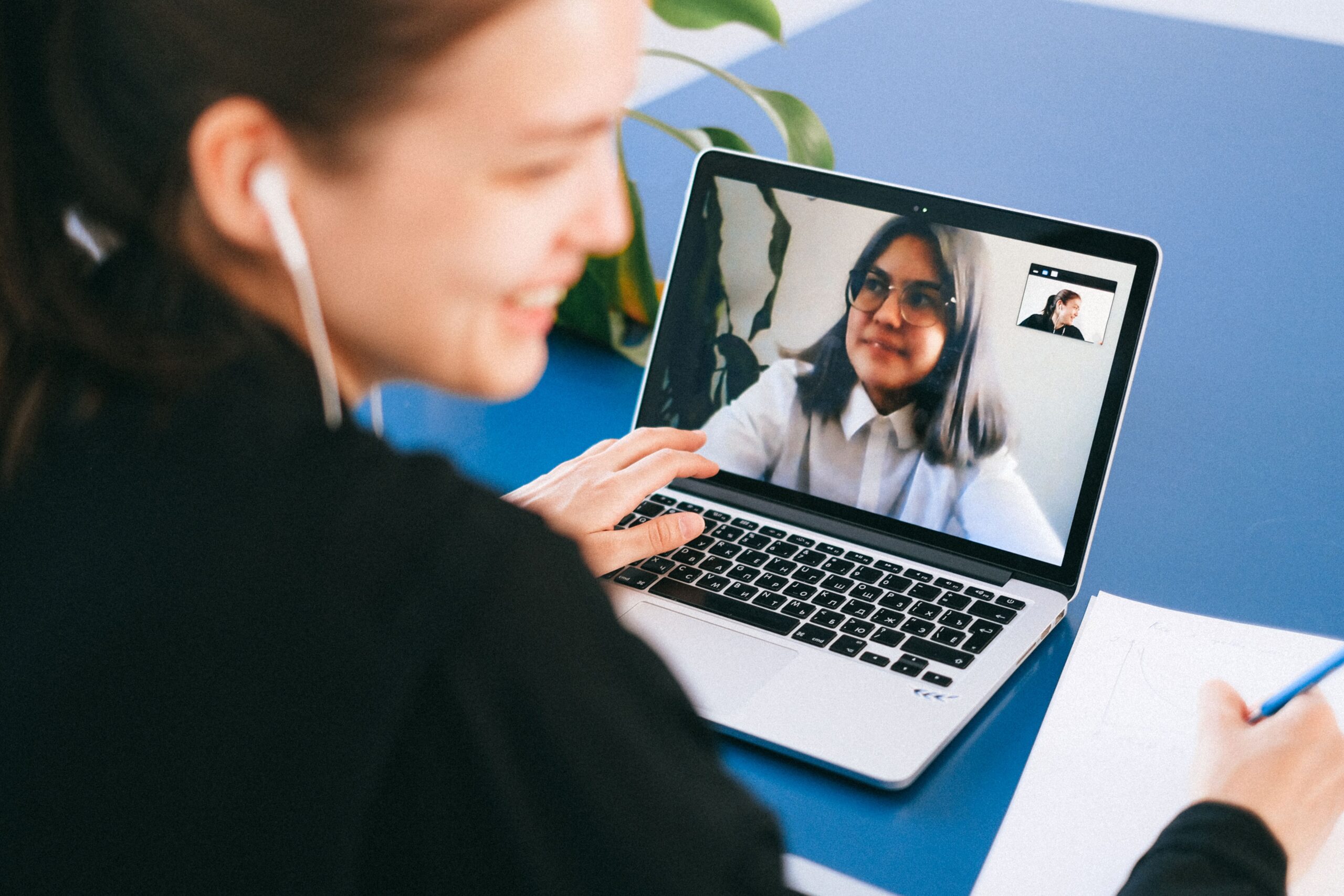 Mujer profesional tomando notas durante una reunión virtual en su laptop