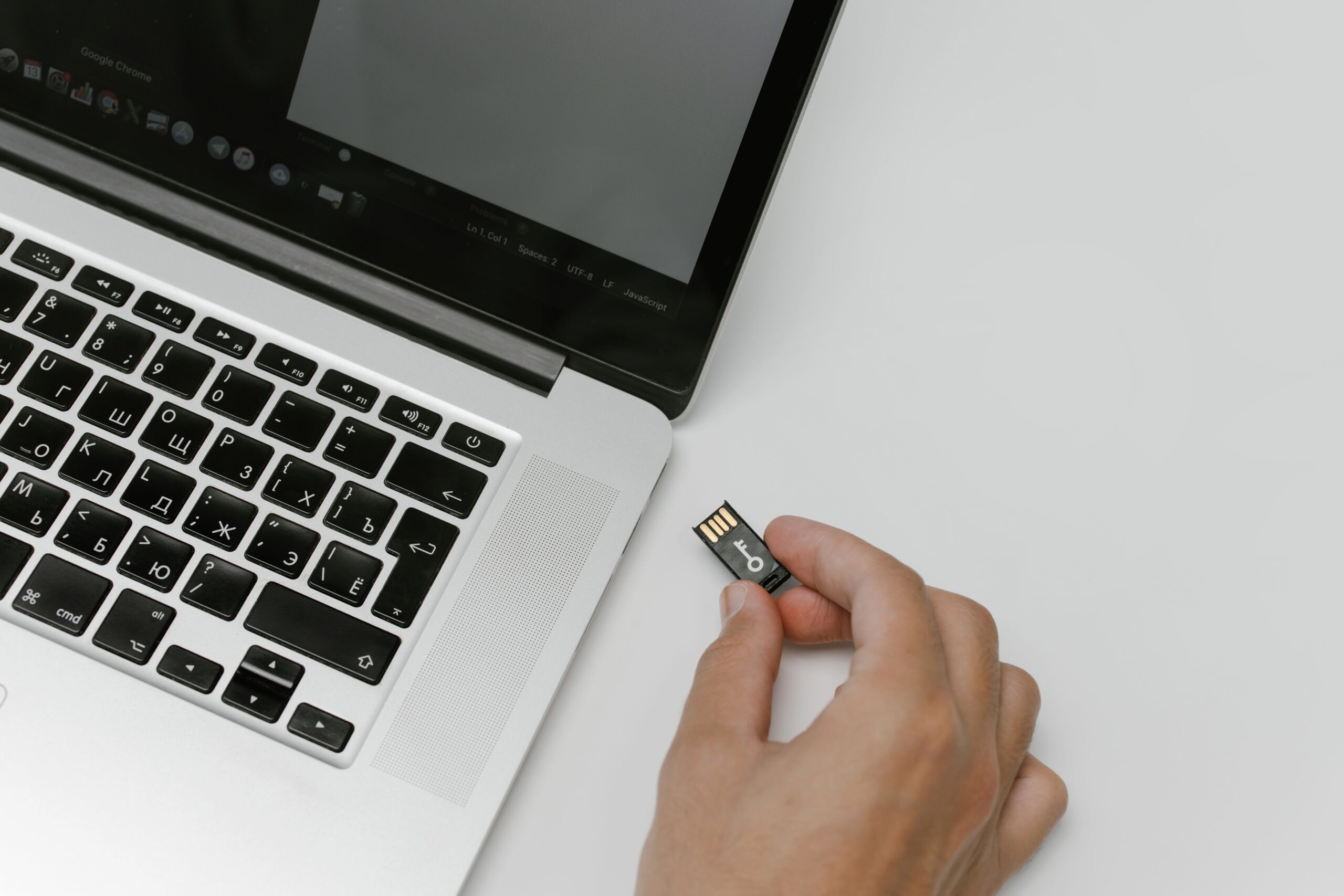 Primer plano de una mano insertando una unidad USB en un ordenador portátil, ideal para ilustrar el proceso de flashear firmware mediante una unidad externa.