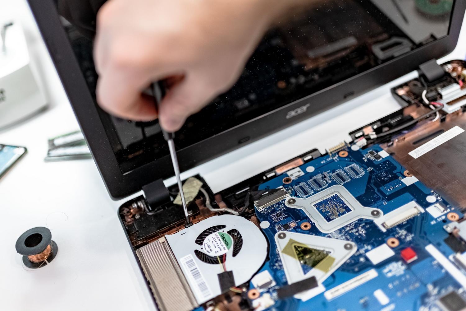 Técnico reparando la placa base de un ordenador portátil, representando la recuperación de datos profesional y fallos de hardware.