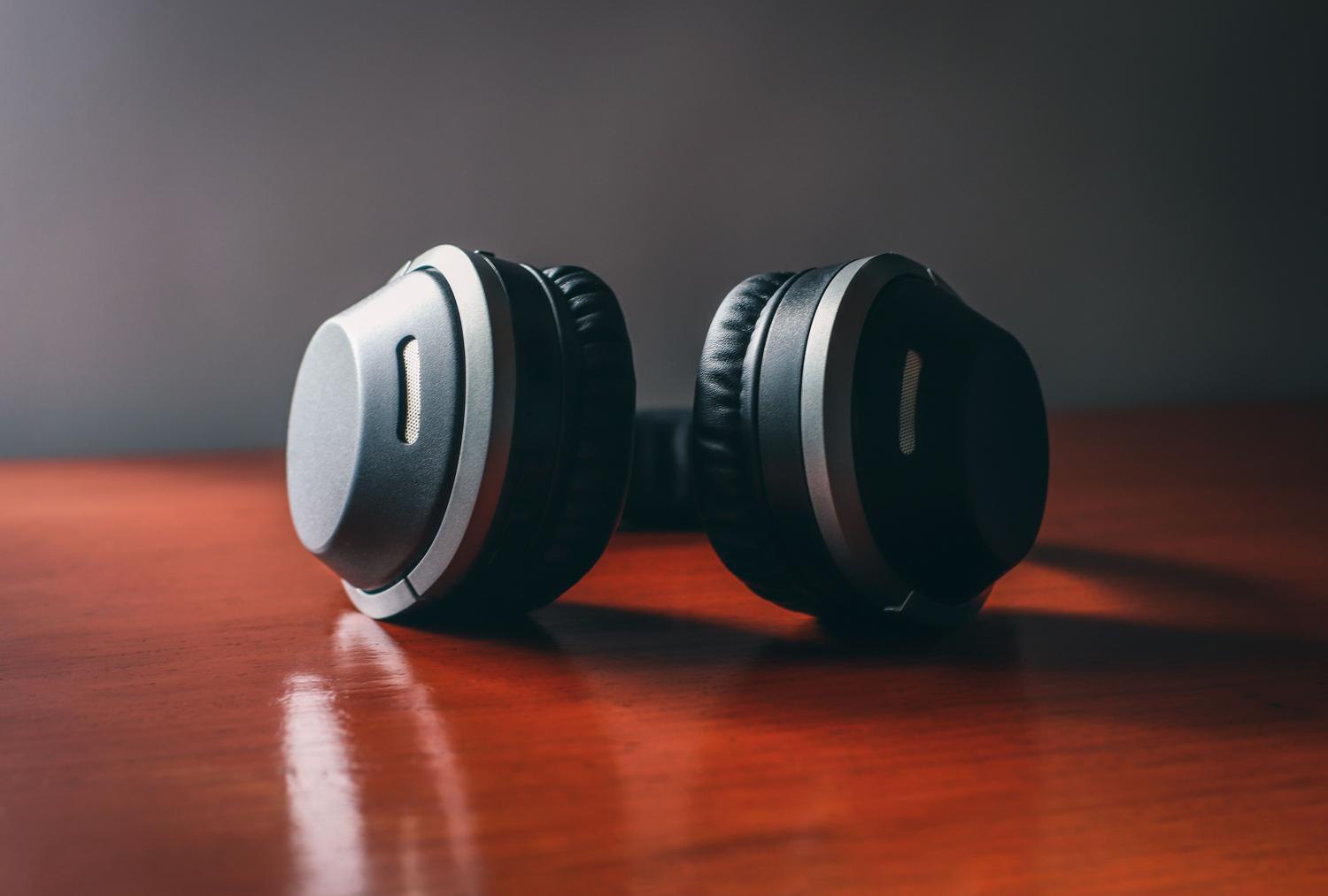 Primer plano de auriculares inalámbricos negros de alta calidad sobre una superficie de madera, ideal para ilustrar la sección de códecs de audio y resolución.