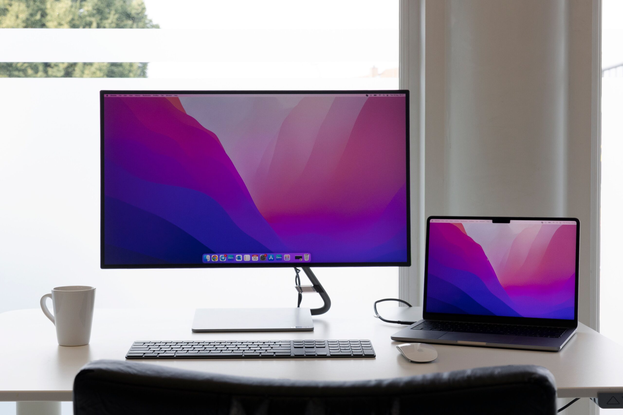 Configuración de oficina tecnológica con monitores duales y un ordenador portátil Apple.