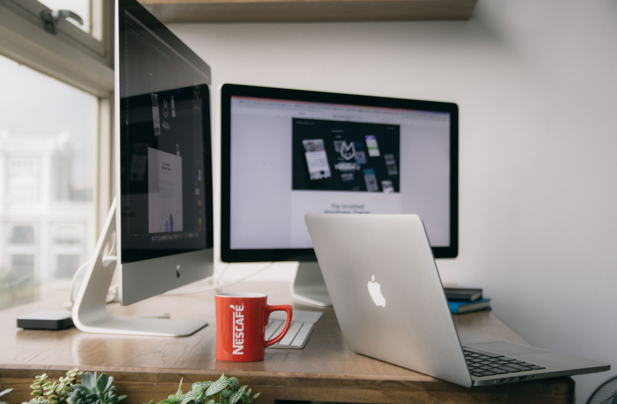 Espacio de trabajo moderno con un MacBook sobre una mesa de madera clara.
