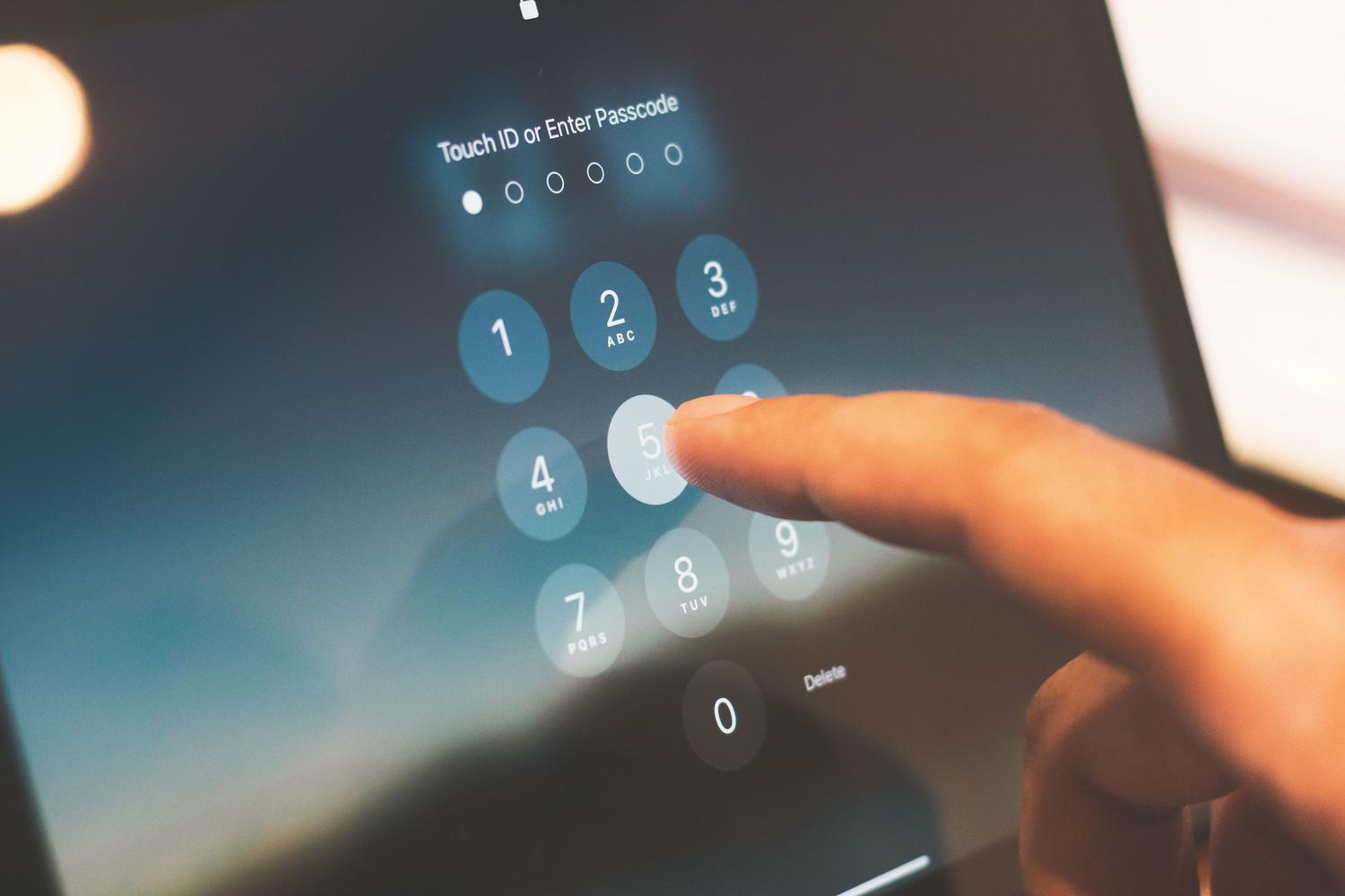 Primer plano de un dedo introduciendo el código de seguridad en la pantalla de bloqueo de un smartphone.