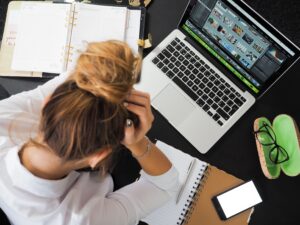 Mujer estresada frente a su MacBook representando la frustración por errores de sincronización de archivos.