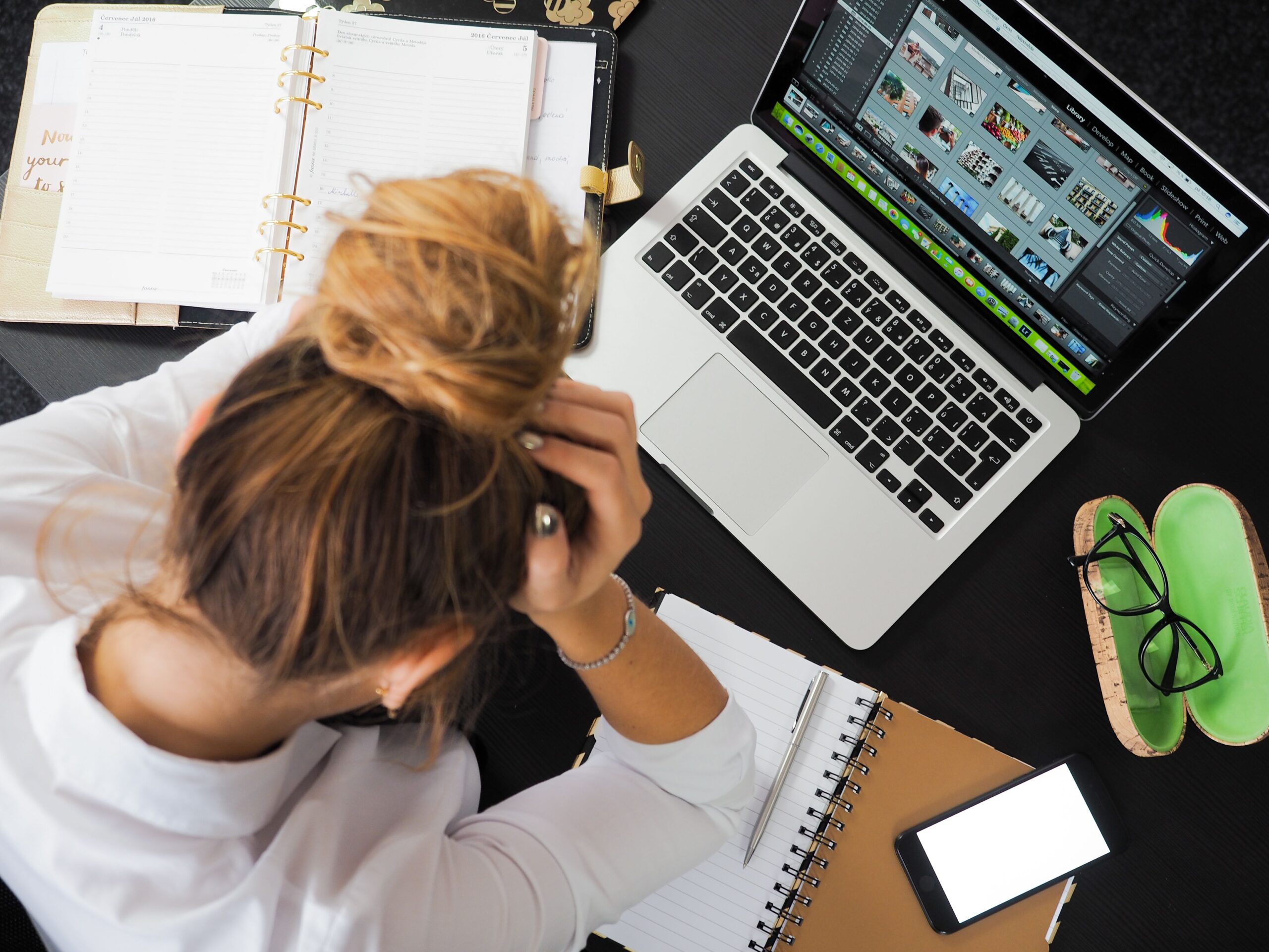 Mujer estresada frente a su MacBook representando la frustración por errores de sincronización de archivos.