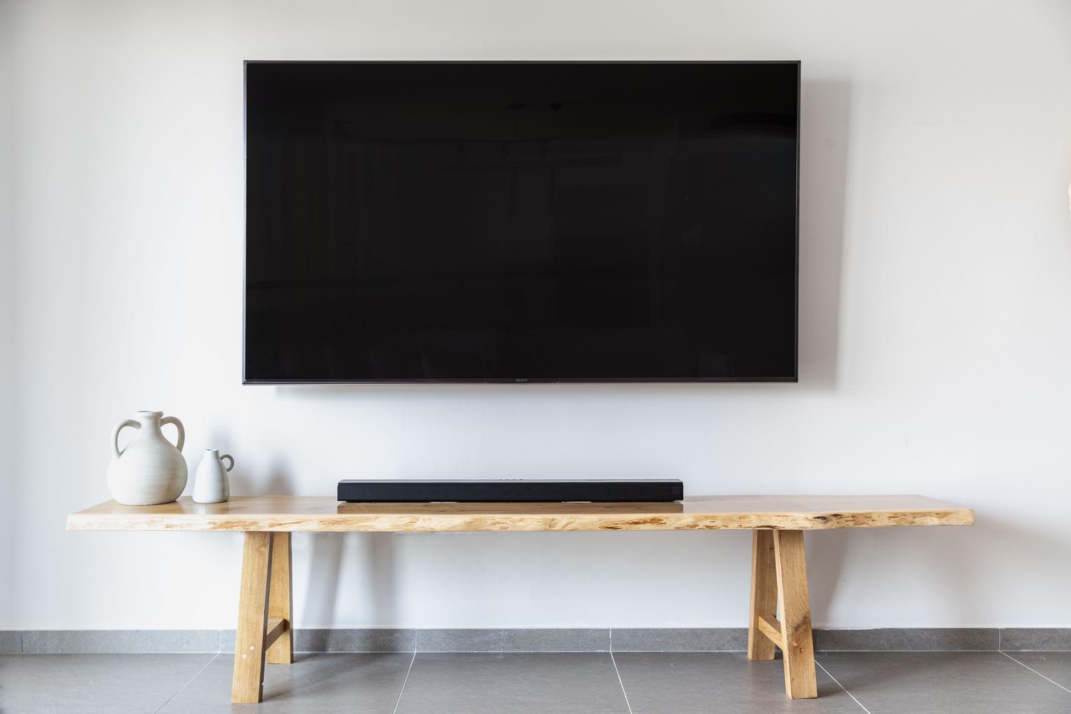 Salón moderno con televisor de pantalla plana montado en la pared, ideal para configurar ajustes de audio y sonido